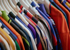 Collection de t-shirts colorés accrochés sur un cintre, avec divers motifs et tissus dans les souks
