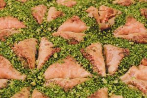 Baklava triangolari al pistacchio, dolci turchi tradizionali con pasta fillo e granella di pistacchio su vassoio.