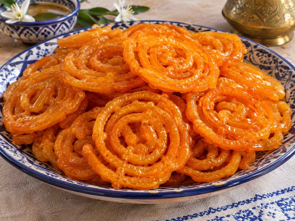 Zlabia tunisina: dischi di pasta fritta a spirale color arancio su un piatto da portata