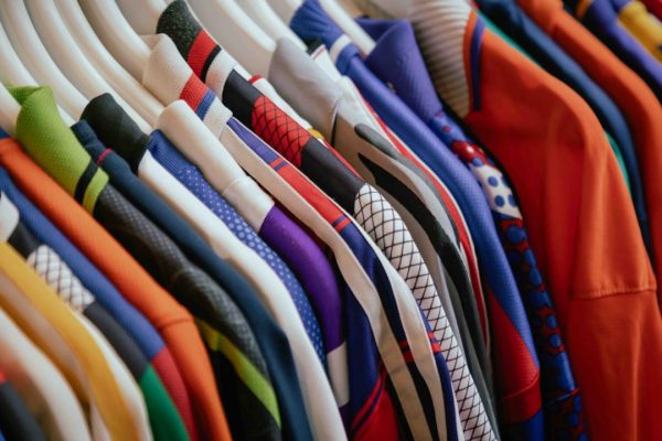 Collezione di magliette colorate appese su una gruccia, con vari motivi e tessuti nei souk